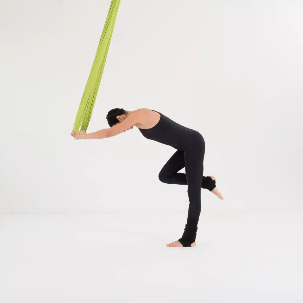 Krieger III im Aerial Yoga Tuch mit nach hinten ausgestrecktem Bein und stabiler Ausrichtung zur Verbesserung der Balance.