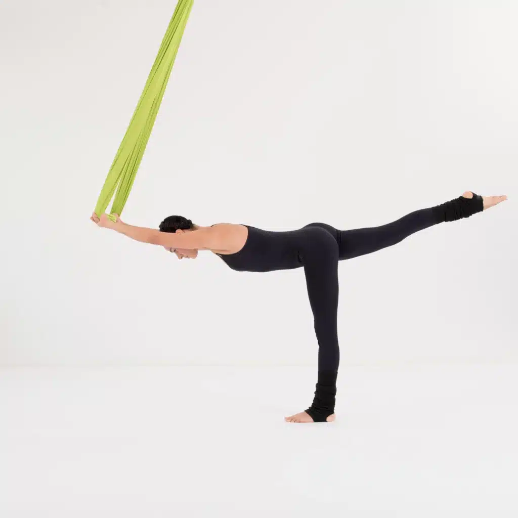 Aerial Yoga Krieger III im Tuch mit gestrecktem hinterem Bein und langer Körperlinie in der Standwaage.