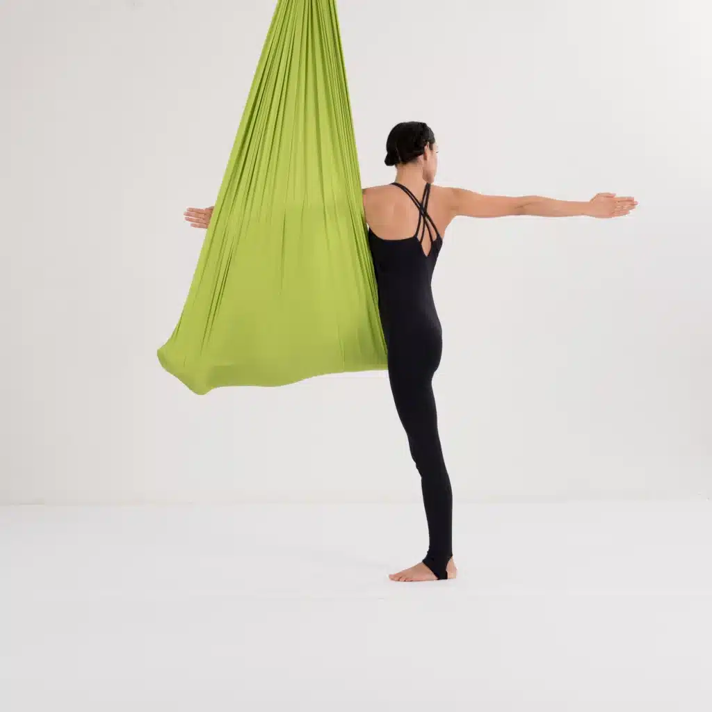 Twist Pose im Aerial Yoga Tuch aus der Rückansicht mit seitlich ausgestreckten Armen zur Verbesserung der Rotation und Balance.