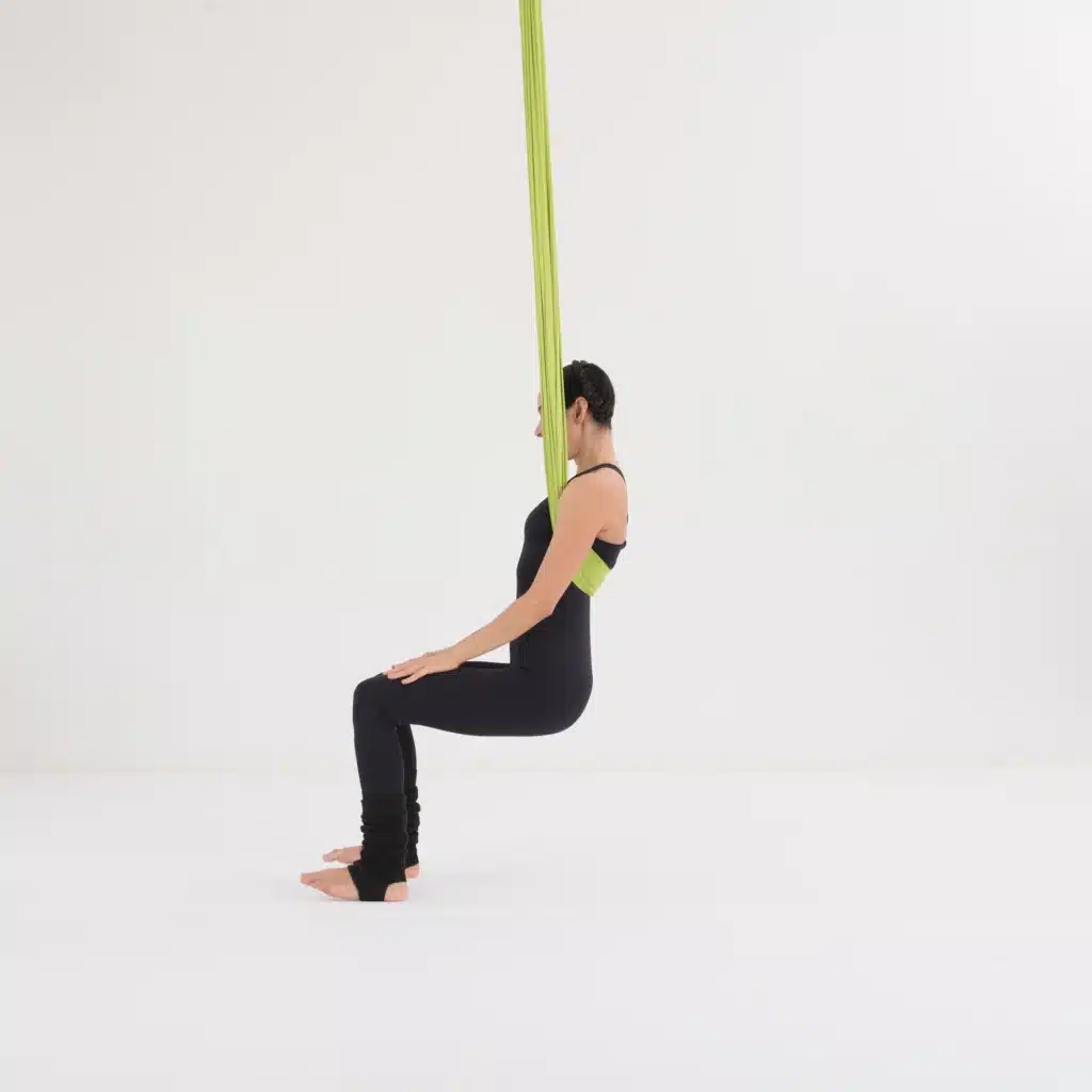 Aerial Yoga Stuhl Position im Aerial Yoga Tuch als Ausgangsposition. Anfänger Übung zur Stabilisierung von Beinen und Core im Yoga Hammock.
