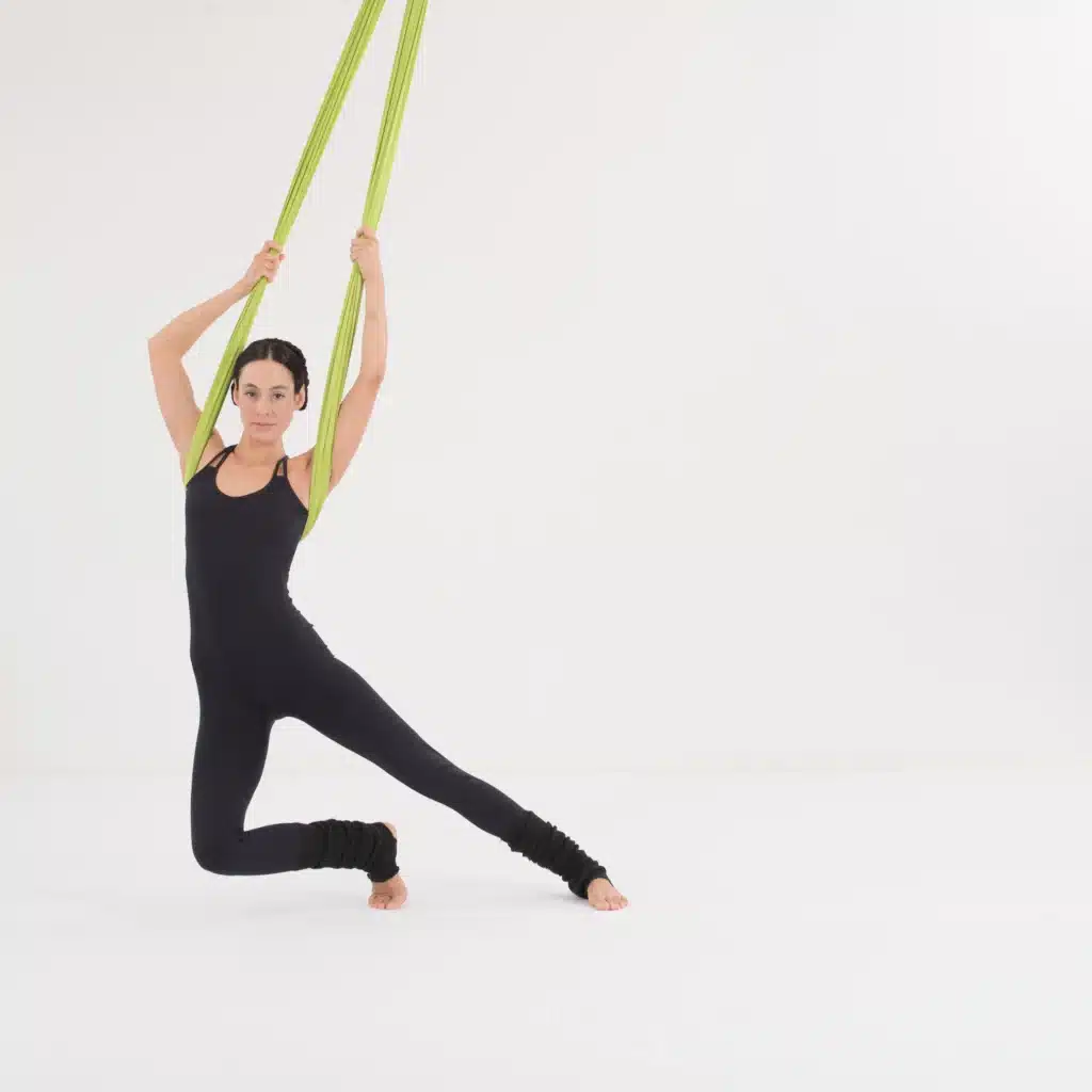 Aerial Yoga Twist und Flow im Aerial Yoga Tuch. Seitliche Bewegung mit gestrecktem Bein zur Mobilisierung der Wirbelsäule und Förderung von Koordination.
