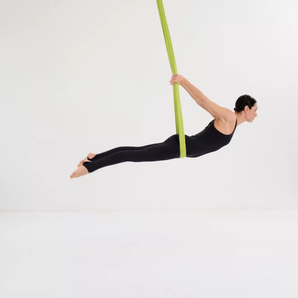 Aerial Yoga Vogel Pose im Tuch mit gestrecktem Körper zur Stärkung von Rücken, Schultern und Körperspannung.