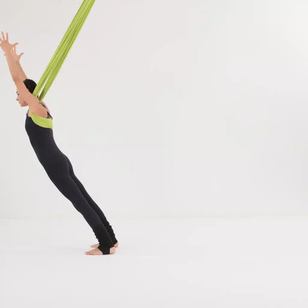 Aerial Yoga Vorwärtsbrett im Aerial Yoga Tuch mit gestreckten Armen. Kräftigende Übung für Core, Schultern und Balance im Aerial Yoga.